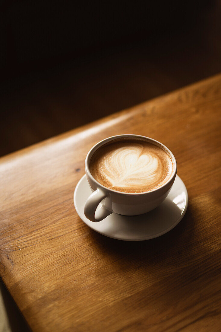 Kaffee in weißer Tasse auf Holztisch, mit Löffel