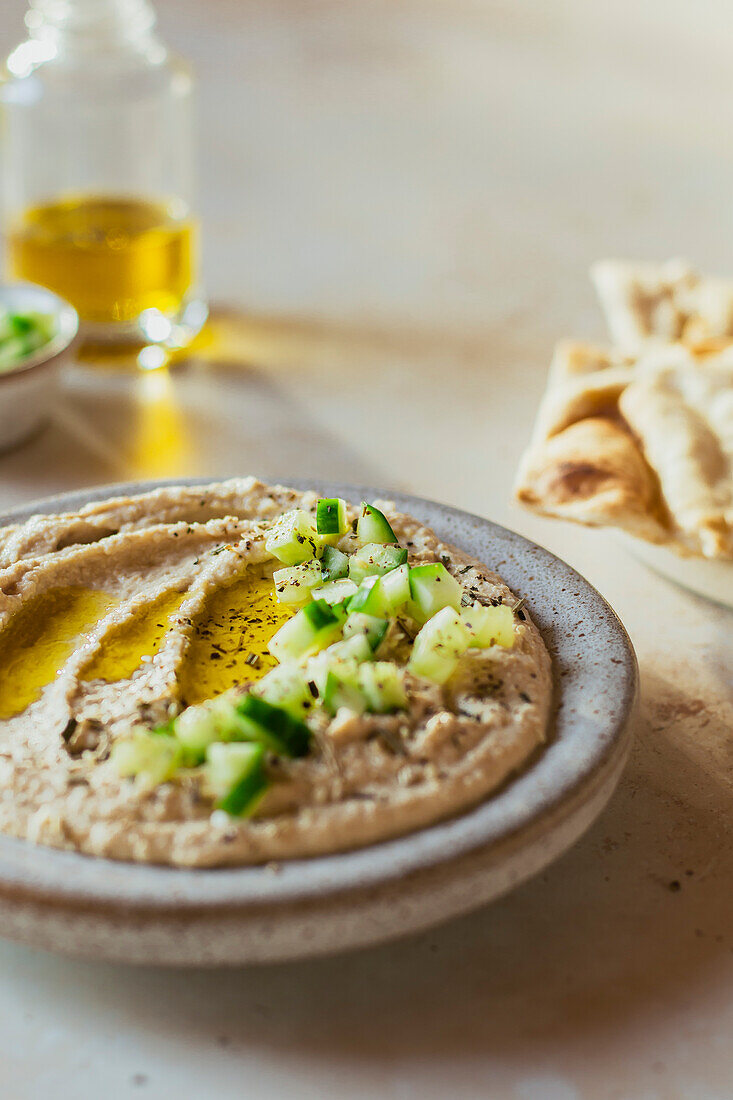 Cremiger Hummus-Dip mit Gurke und Olivenöl übergossen