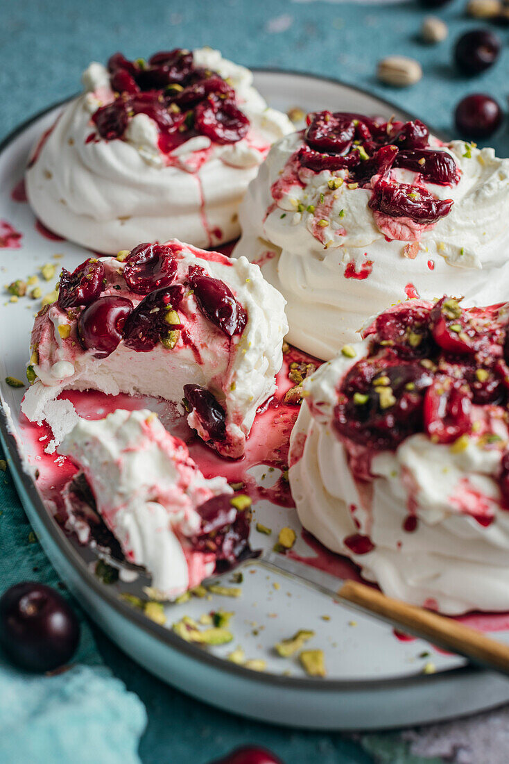 Meringues with fresh cream and ripe cherries on a blue background