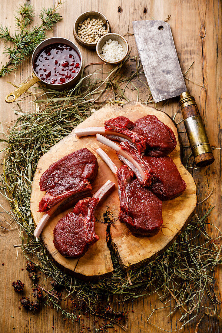 Raw, sliced venison ribs and meat cleaver on a wooden background