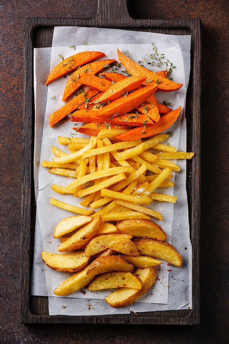 Various potatoes for garnishing: Potato wedges, French fries, sweet potatoes on a brown background