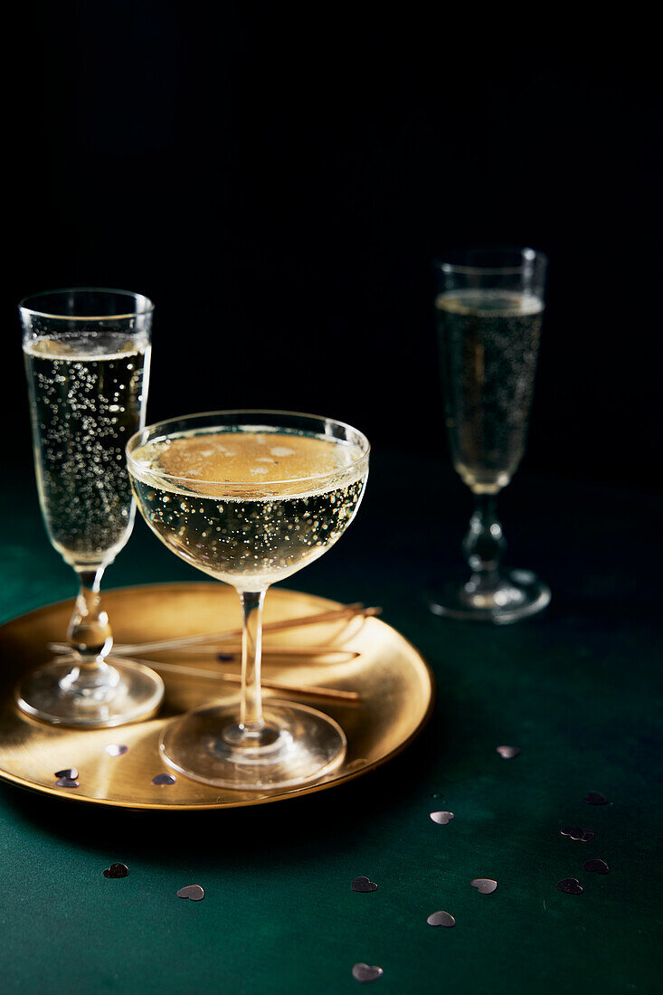 Prosecco glasses and golden plate on green background