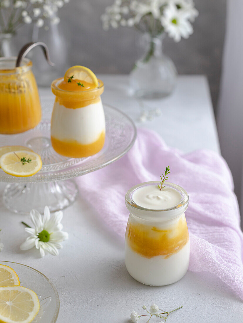 Lemon curd and Greek yoghurt with thyme in glass jars. Gentle romantic scene