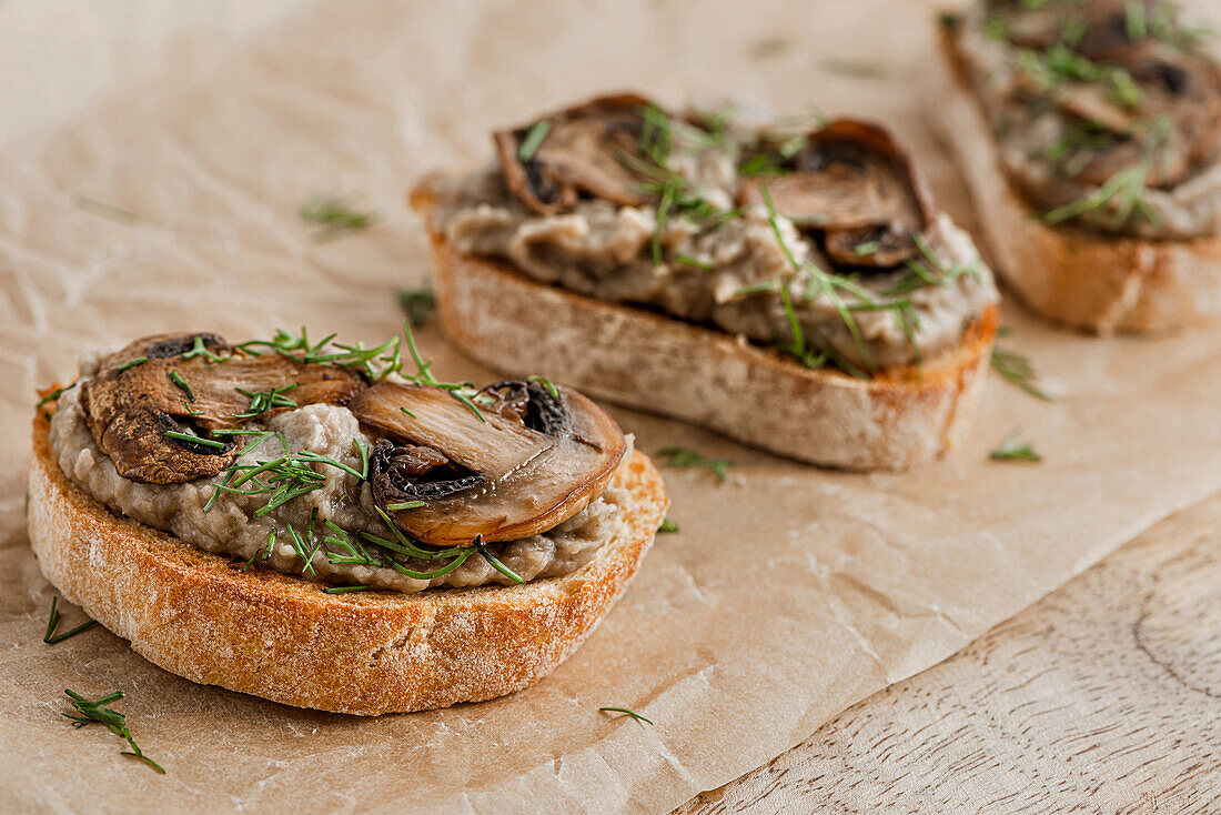 Sandwiches mit Pilzpastete und Champignons auf Kraftpapier