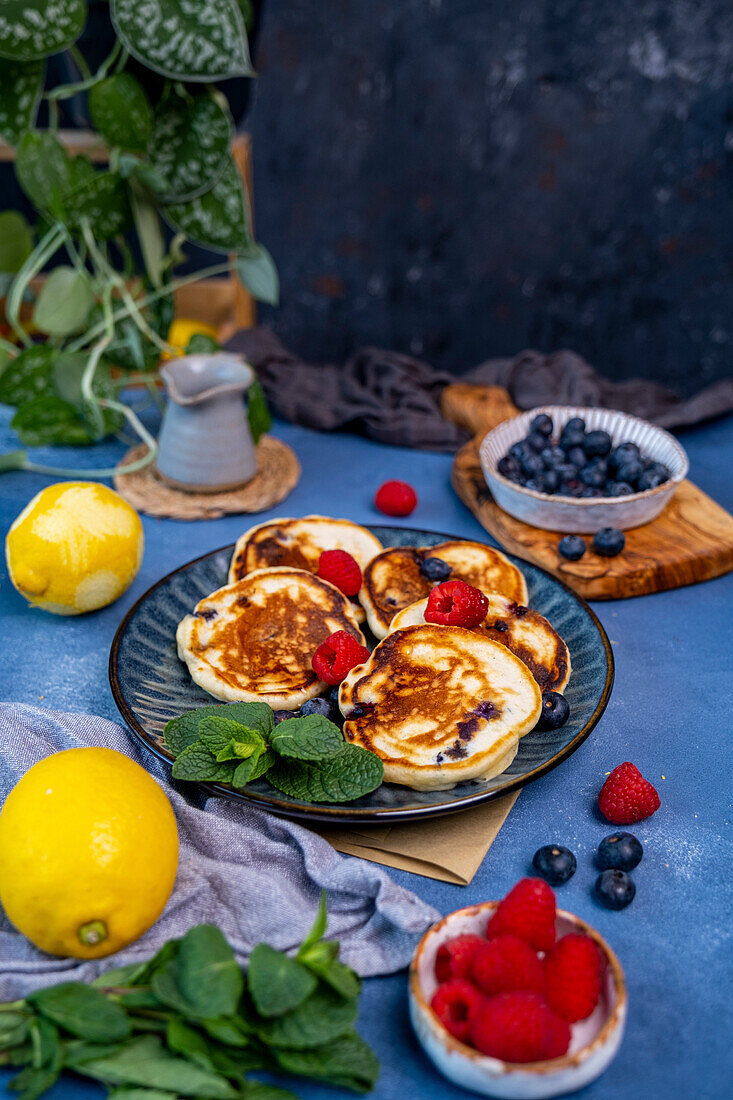 Lemon and blueberry pancake garnished with blueberries and raspberries on a dark plate