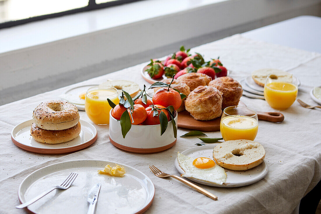 Frühstückstischlandschaft mit Gebäck, Orangensaft und Obst