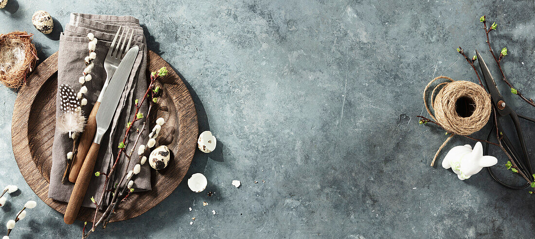 Easter table with spring flowers and cutlery on dark blue background, top view, flat lay. Happy Easter concept for cafés and restaurants. Copy space