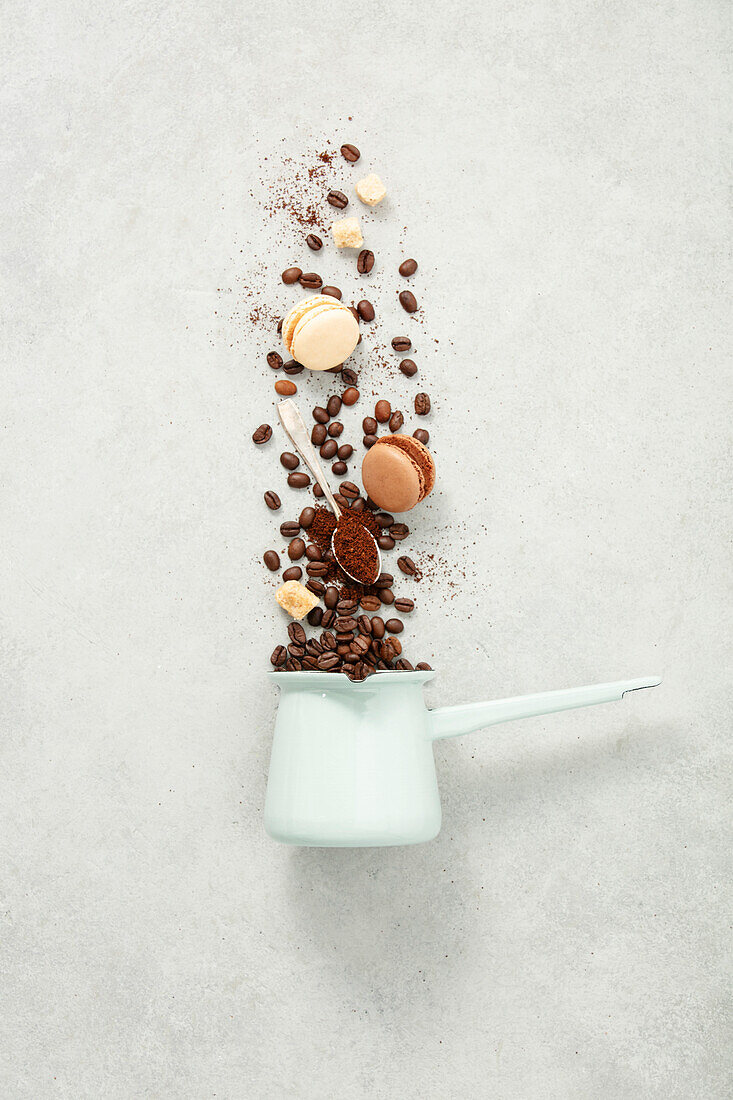 Coffee turk and flying coffee beans and macarons on concrete background flat lay