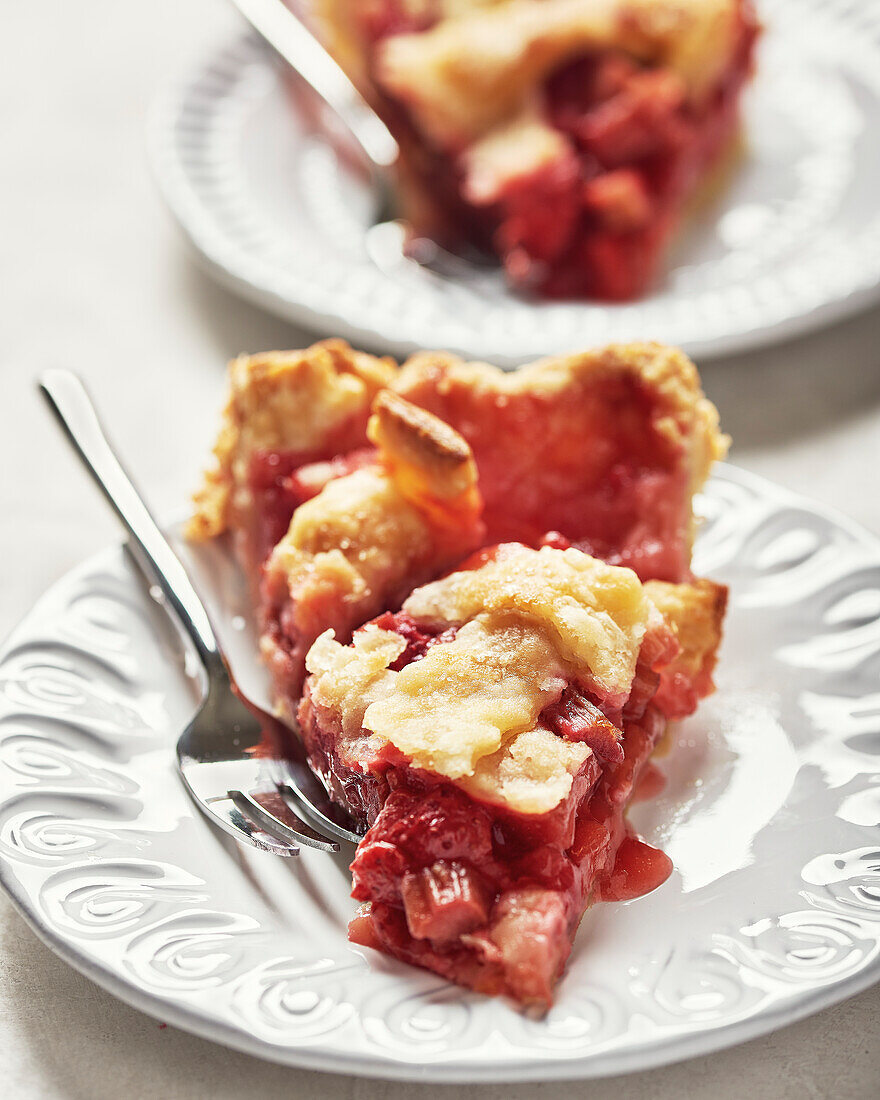 Veganer Erdbeer-Rhabarber-Kuchen mit frischen Erdbeeren auf hellem Hintergrund