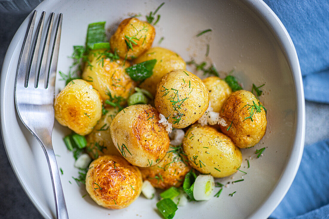 Top roasted spring potato vegetables with herbs, served in a bowl for lunch