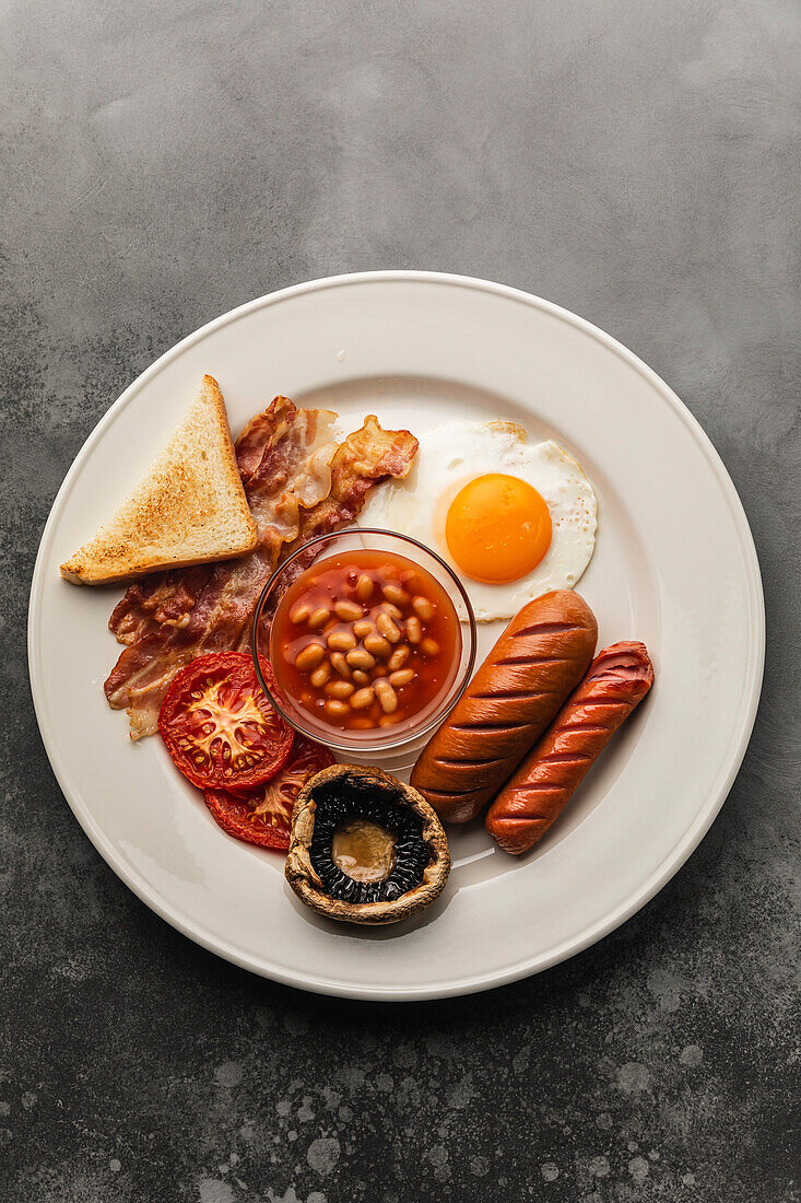 Komplettes englisches Frühstück mit Spiegeleiern, Würstchen, Speck, Bohnen und Toast
