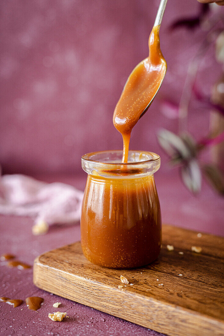 A spoon in a glass with homemade caramel sauce