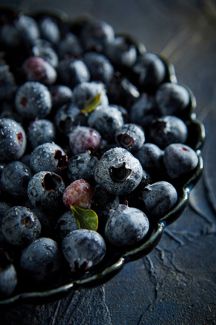 Blaubeeren mit Wassertröpfchen vor blauem Hintergrund