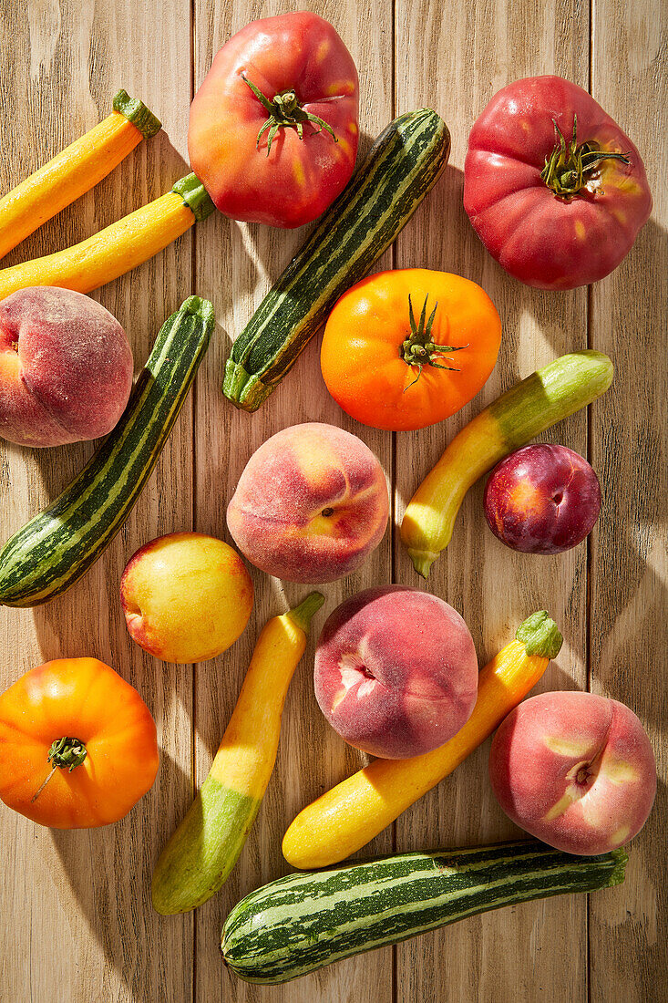 Tomatoes, courgettes and stone fruit on a wooden base