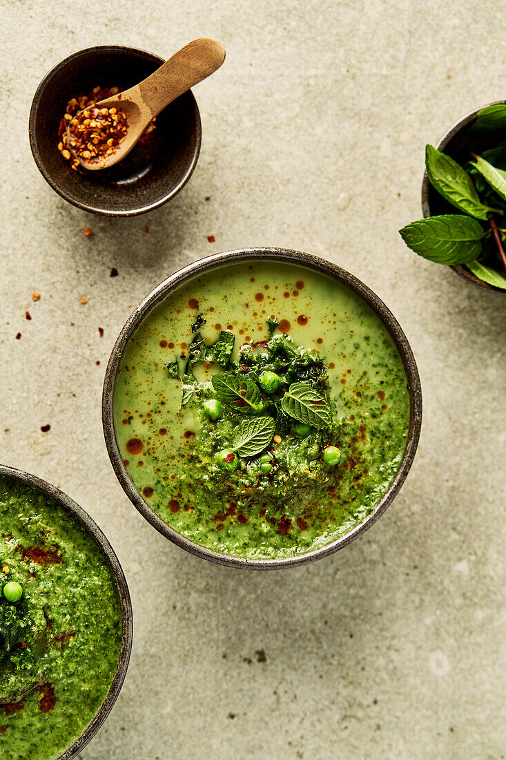 Pea and mint and kale soup on a light green background with chilli