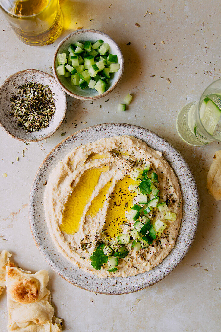 Creamy hummus dip with cucumber and olive oil flatlay