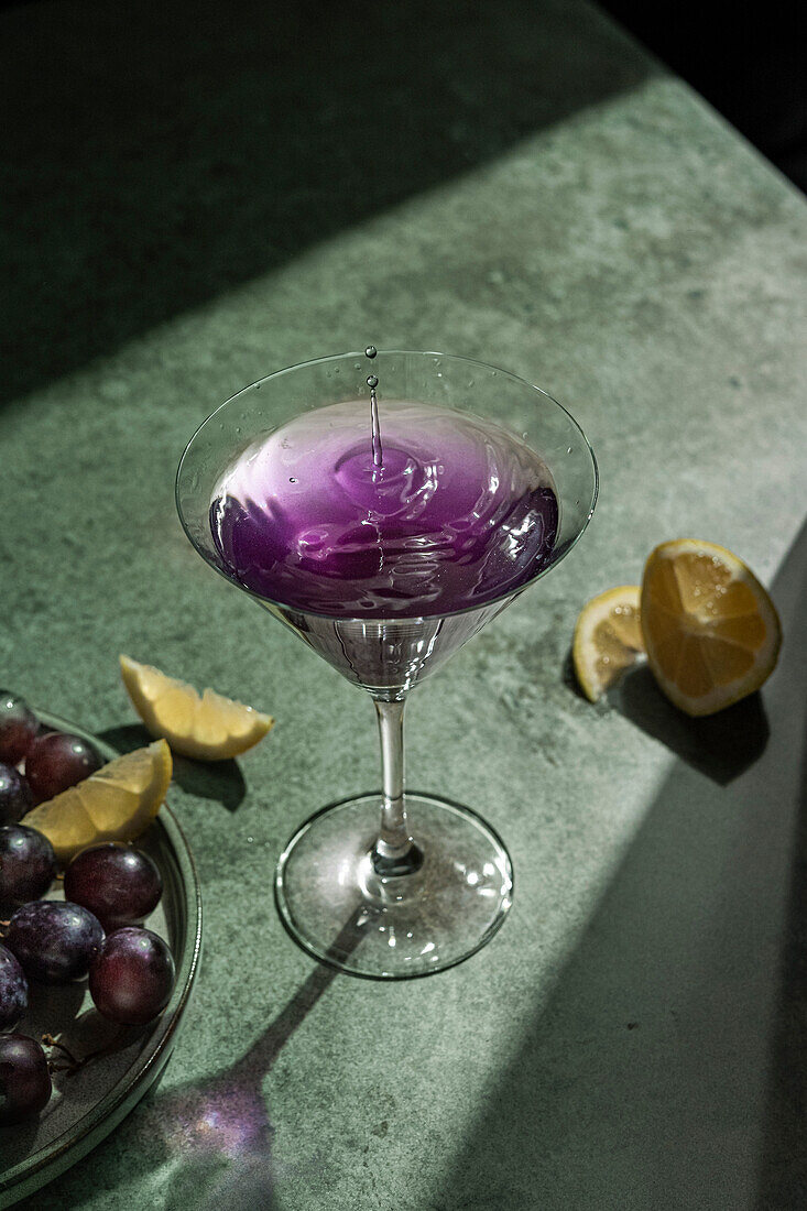 Martini glass with purple drink on a green background