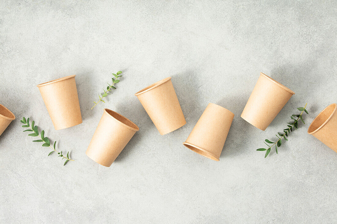 Flat lay composition with eco-friendly paper cups on grey stone background. Abfallfreies Verpackungskonzept