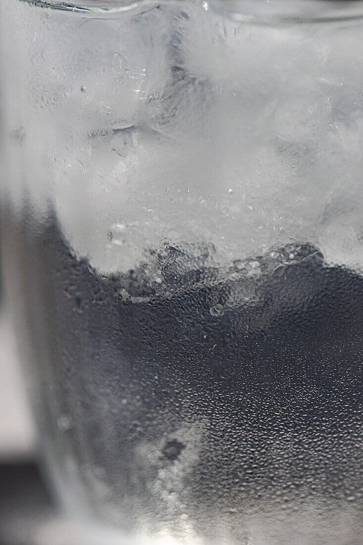 Close up of glass of pure water with ice cubes in hot summer day