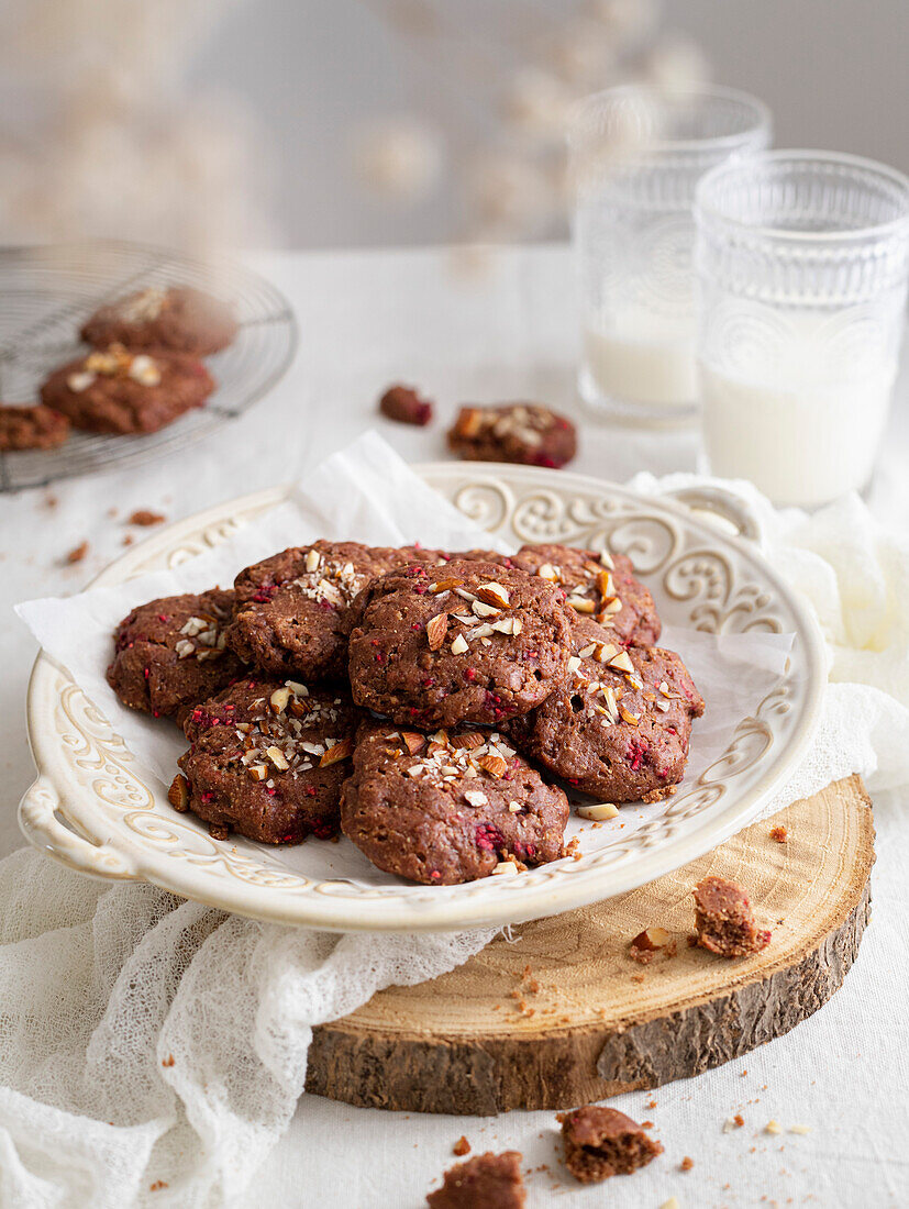 Vegan chocolate and raspberry biscuits on a vintage tray, served with two glasses of milk