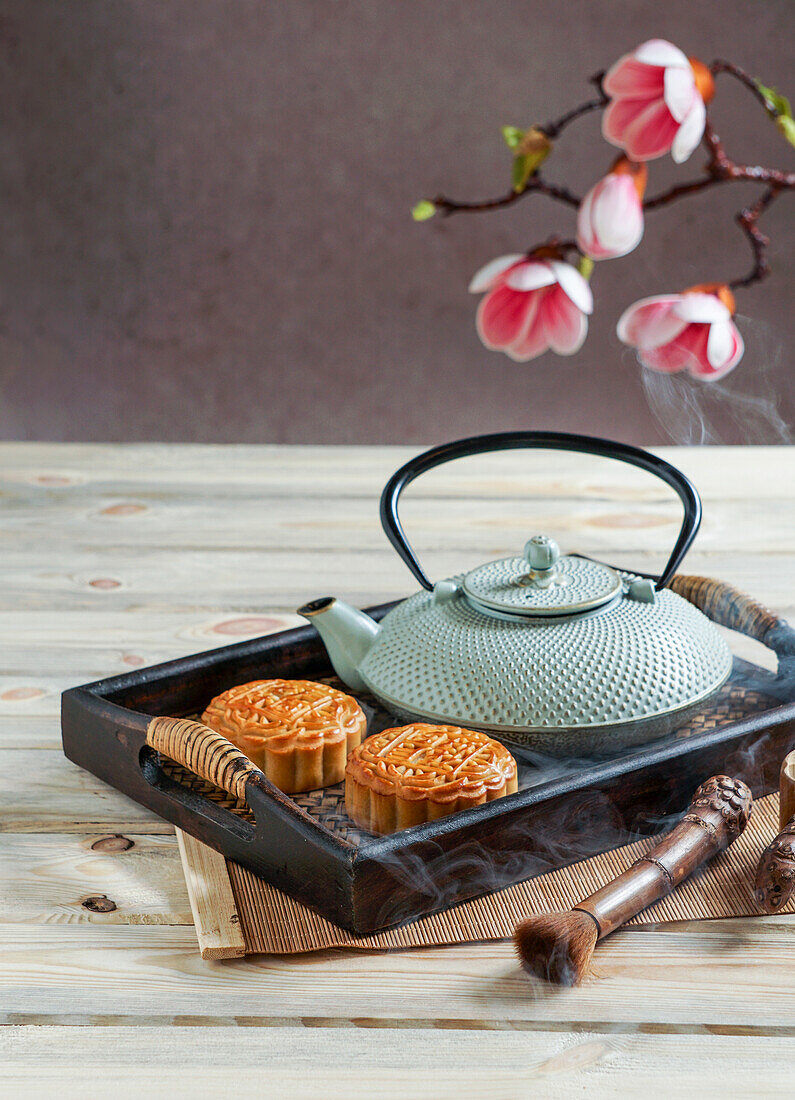 Mondkuchen zum Mittherbstfest, Konzept für traditionelles chinesisches Festessen auf einem asiatischen Holztablett mit Teekanne