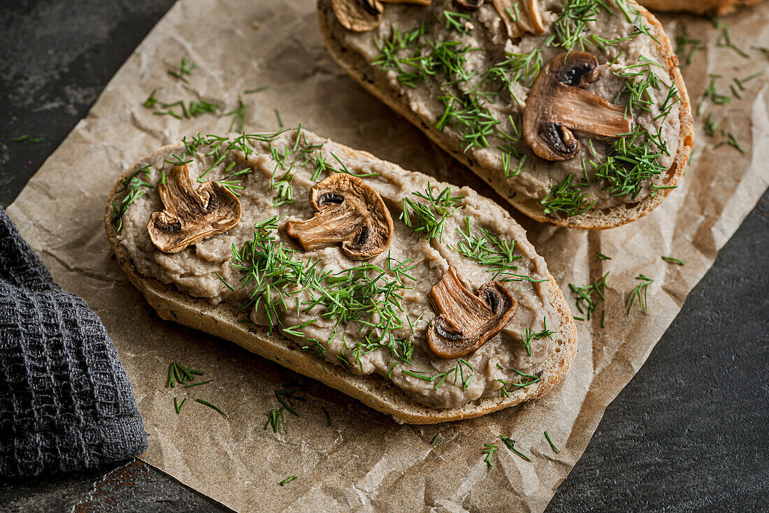 Sandwiches mit Pilzpastete und Champignons auf Kraftpapier