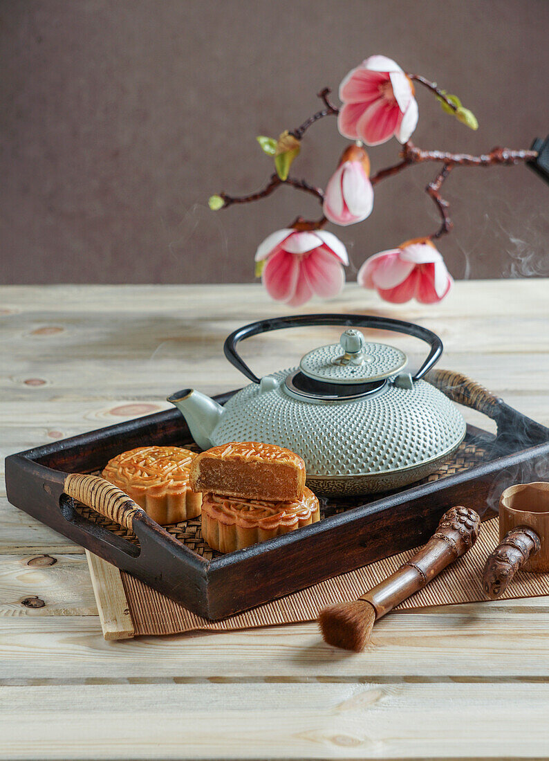 Mooncake for the Mid-Autumn Festival, concept for traditional Chinese feast on an Asian wooden tray with teapot
