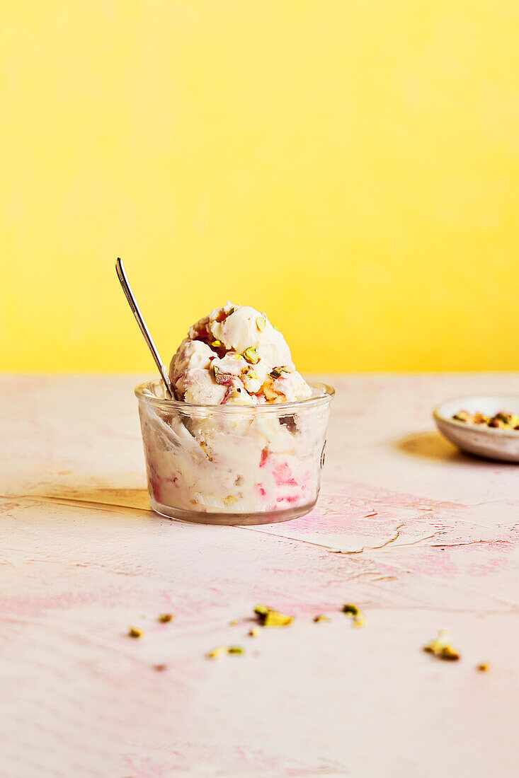 Raspberry ripple ice cream with pistachios on a pink-yellow background with 1 portion