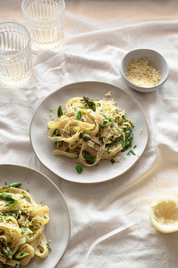 Lemony pasta with asparagus, vegan cheese and fresh basil on a spring-like, airy table