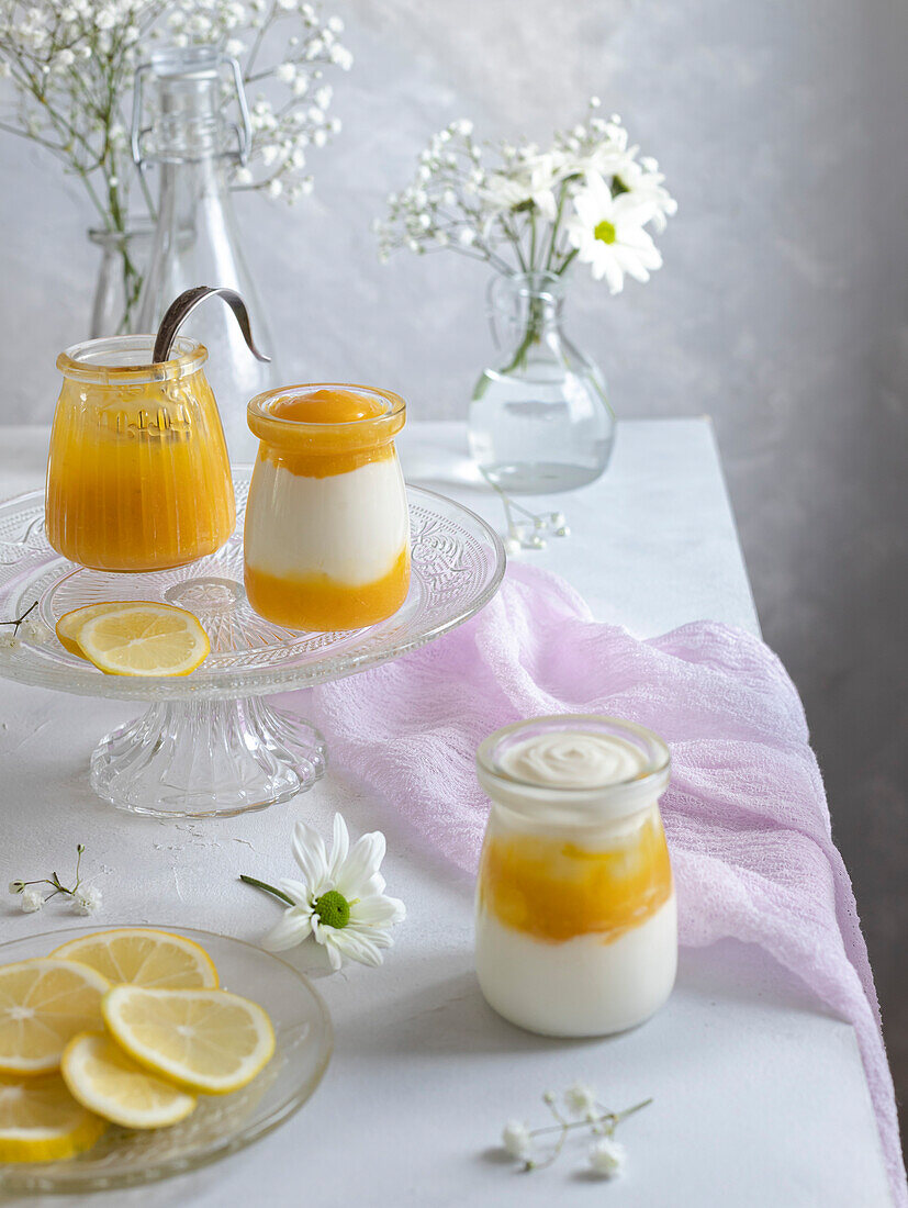 Lemon curd and Greek yoghurt with thyme in glass jars. Gentle romantic scene