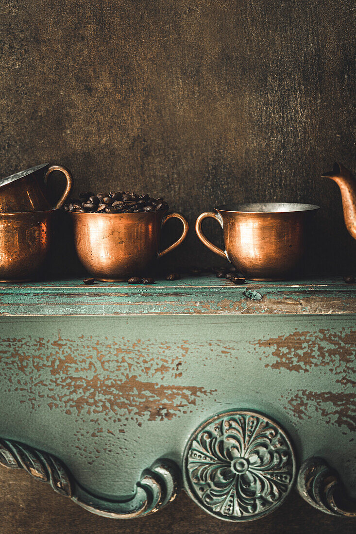Coffee beans in a copper mug on a shelf in a rustic kitchen