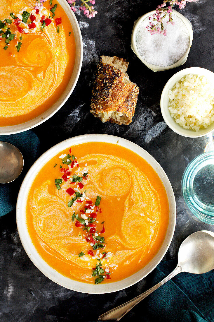 Red lentil-piquillo-paprika bisque in white bowls with blue napkins