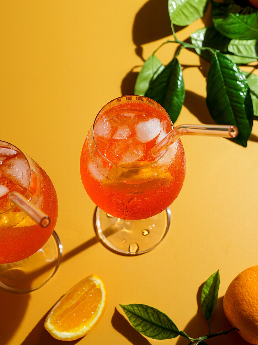 aperol spritz cocktail with ice, a misted refreshing drink, on an orange background, sunlight, shadows, a summer drink in a wine glass