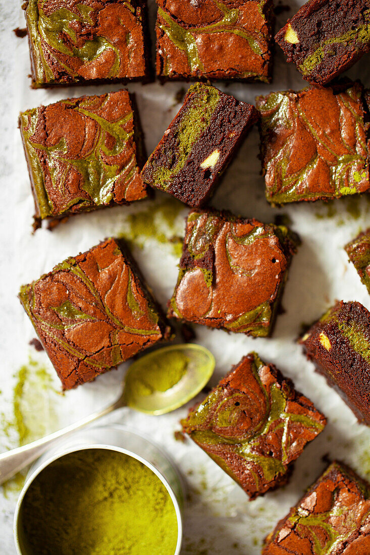 Squares of matcha chocolate brownie with a tin of matcha powder.
