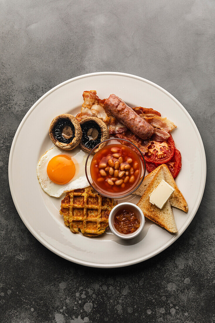 Full English breakfast with fried eggs, sausages, bacon, beans and toast