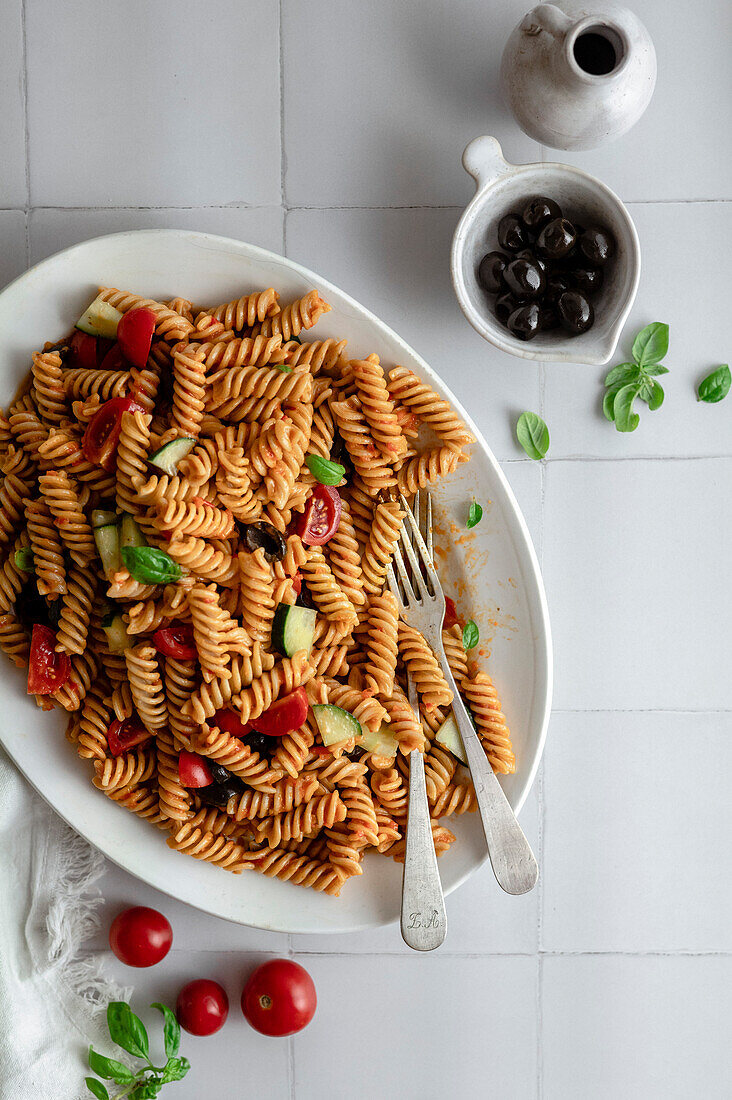 Mediterranean pasta bowl with fresh basil, olives, cherry tomatoes and cucumber
