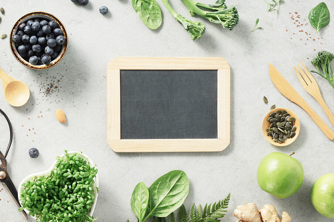 Vegetarian vegan healthy ingredients and blank chalkboard on grey stone background. Healthy food, eco-friendly, zero waste concept