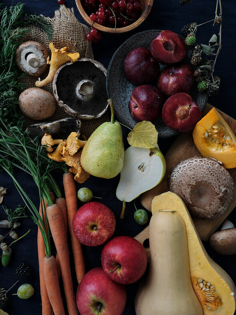 Herbst Lebensmittel Zutaten auf dunkelblauem Hintergrund. Flat-Lay von Herbstgemüse, Beeren und Pilzen aus dem lokalen Markt. Vegane Zutaten