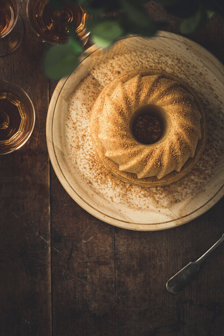 Traditional circular orange Bundt Cake on a wooden table, with copy space