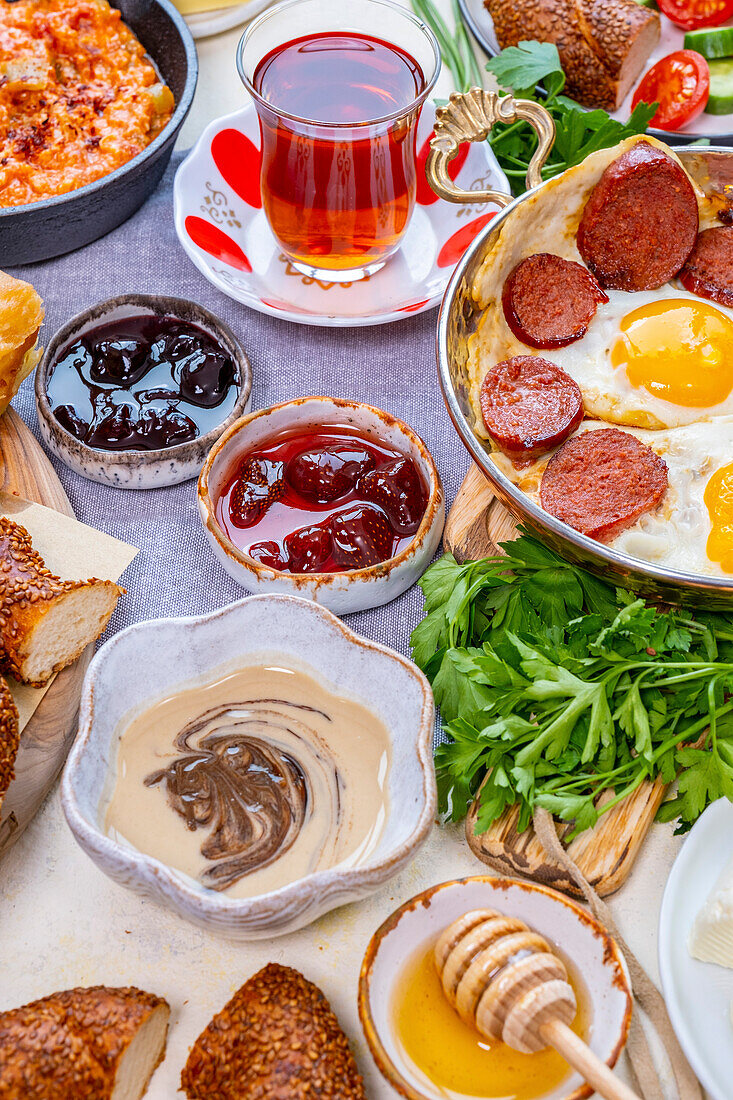 Tahin pekmez in a bowl and other Turkish breakfast foods such as jams, eggs and sujuk, menemen and Turkish tea behind it