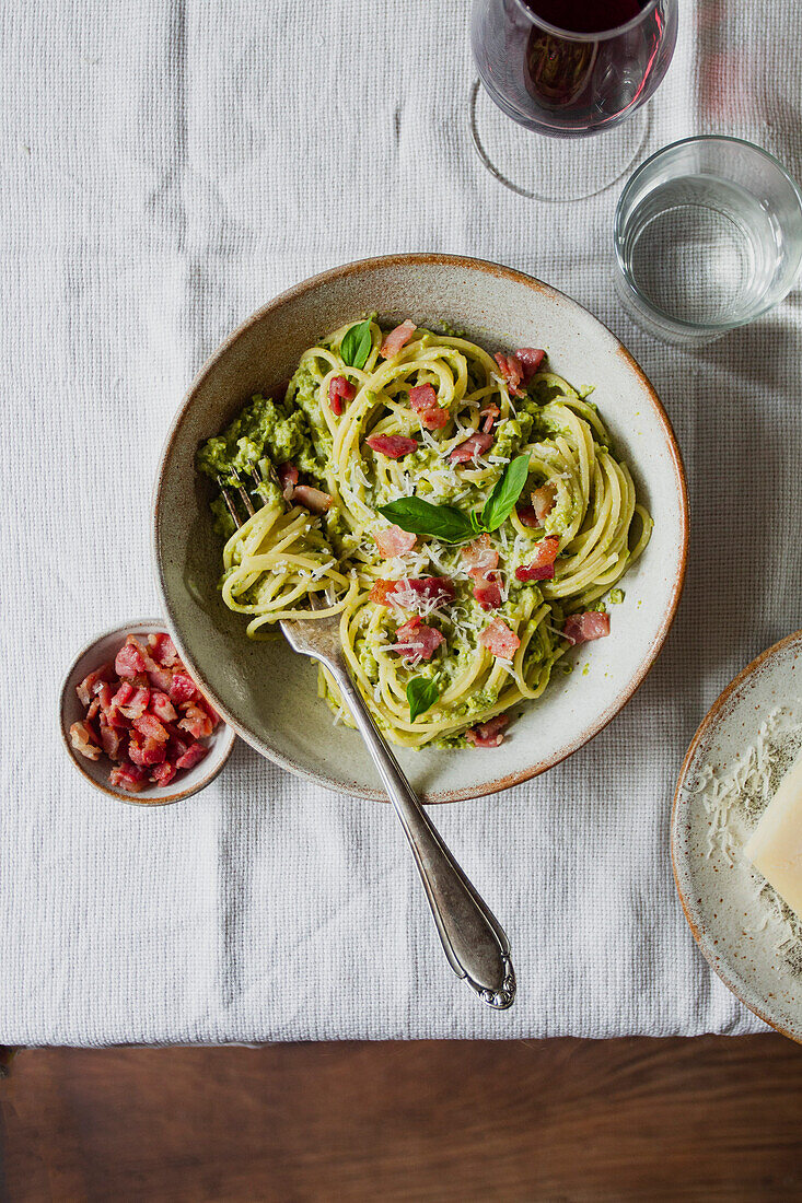 Bowl of spaghetti with fresh basil, pancetta, parmesan and a glass of red wine