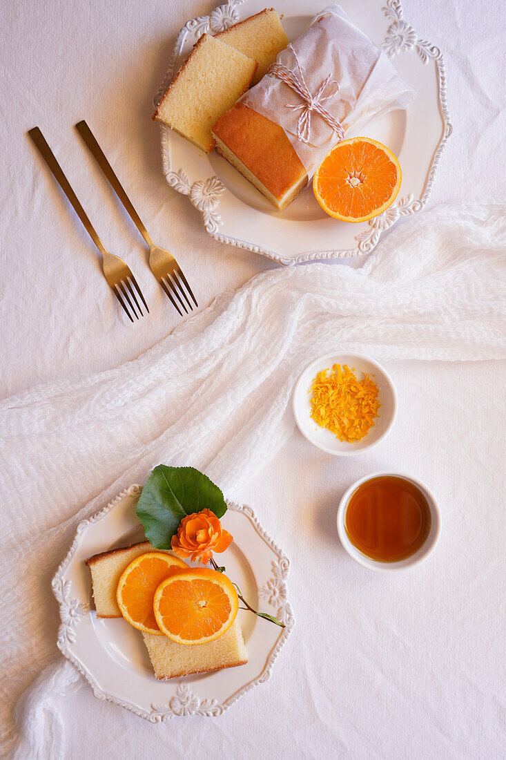 Orangen-Madeira-Kuchen mit Sirup und Orangenschalen. Tischdekoration für den Nachmittagstee Flatlay