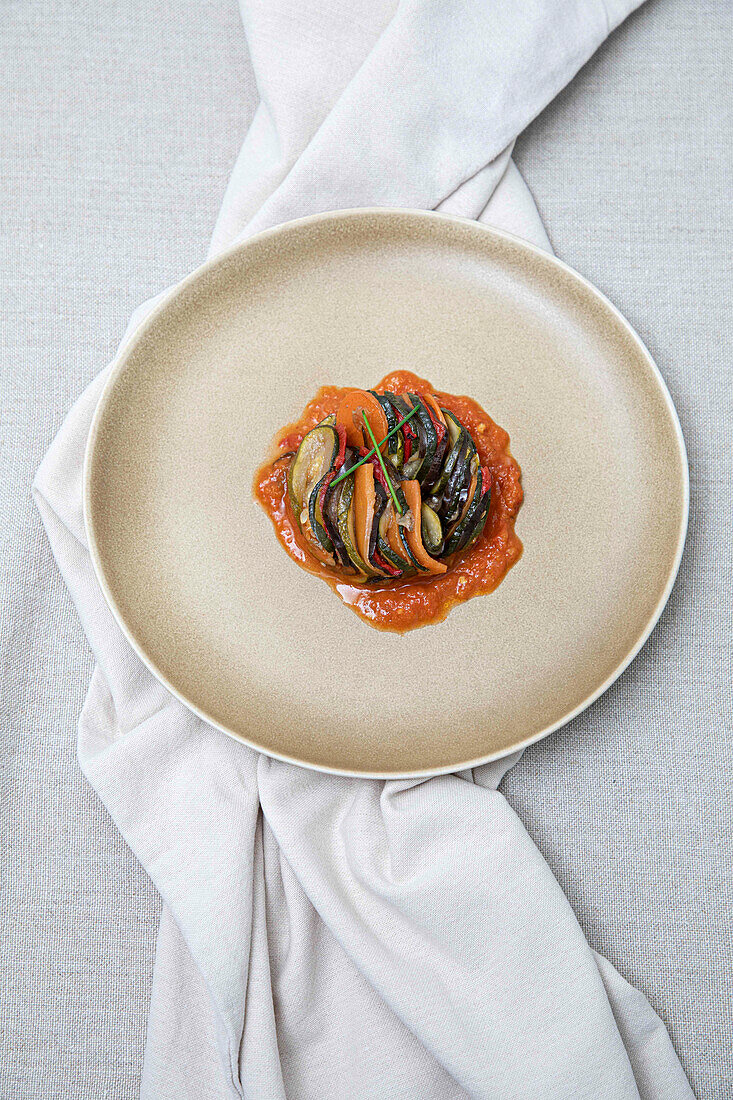 A modern take on ratatouille or mixed steamed vegetables, served on a ceramic plate