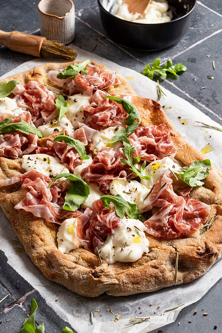 Pizza with prosciutto, rocket, cheese and olive oil
