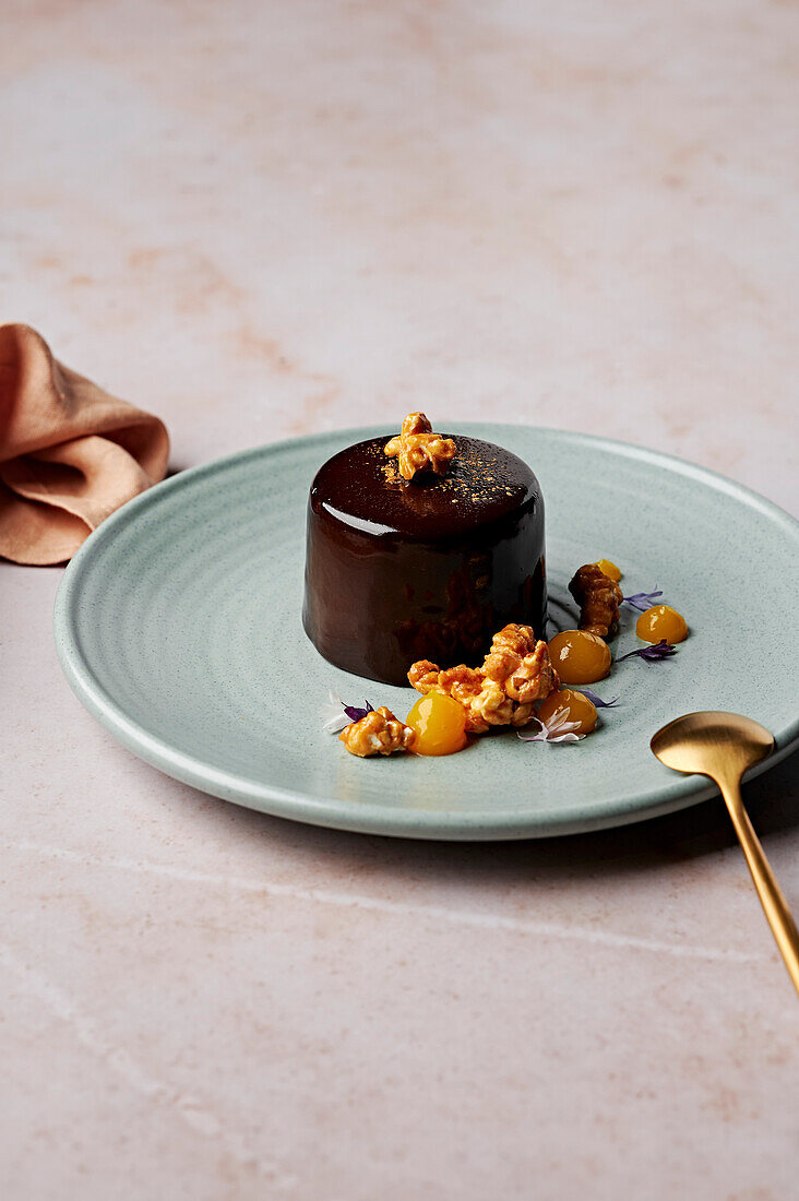 Flourless chocolate cake with mirror glaze, salted caramel popcorn and mandarin gel