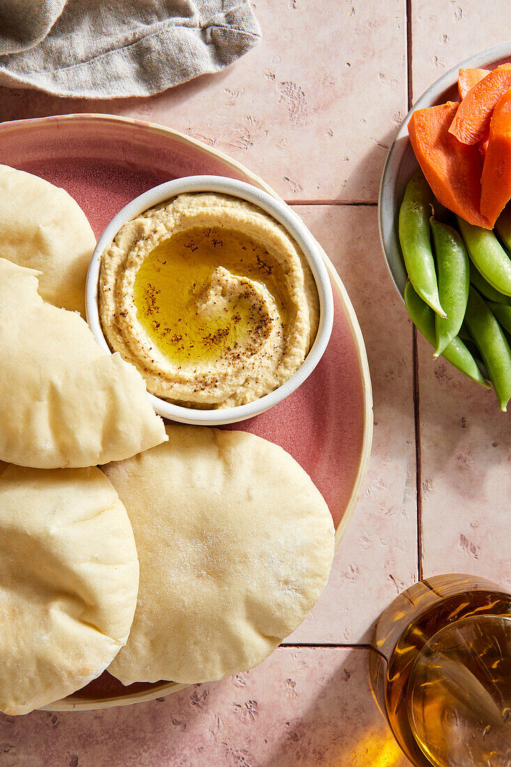 Fladenbrot und Hummus auf rosa Fliese