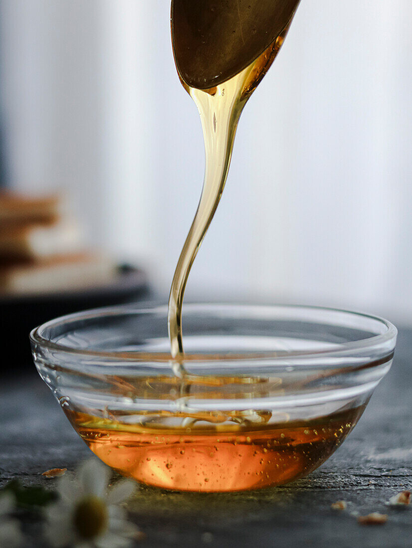 Honey drip on a glass bowl with a spoon