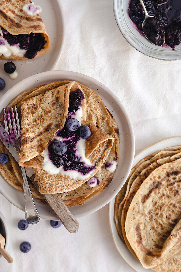 Crepes with brueberry jam and yogurt in table with a light atmosphere, breakfast