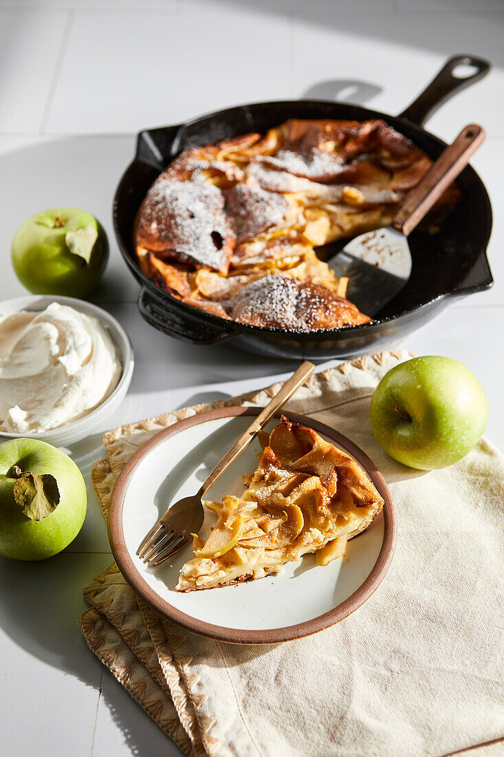 Deutscher Apfelpfannkuchen mit Pfanne und Tellern