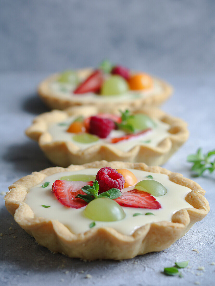 Fresh fruit and custard cream tart decorated with mint leaves